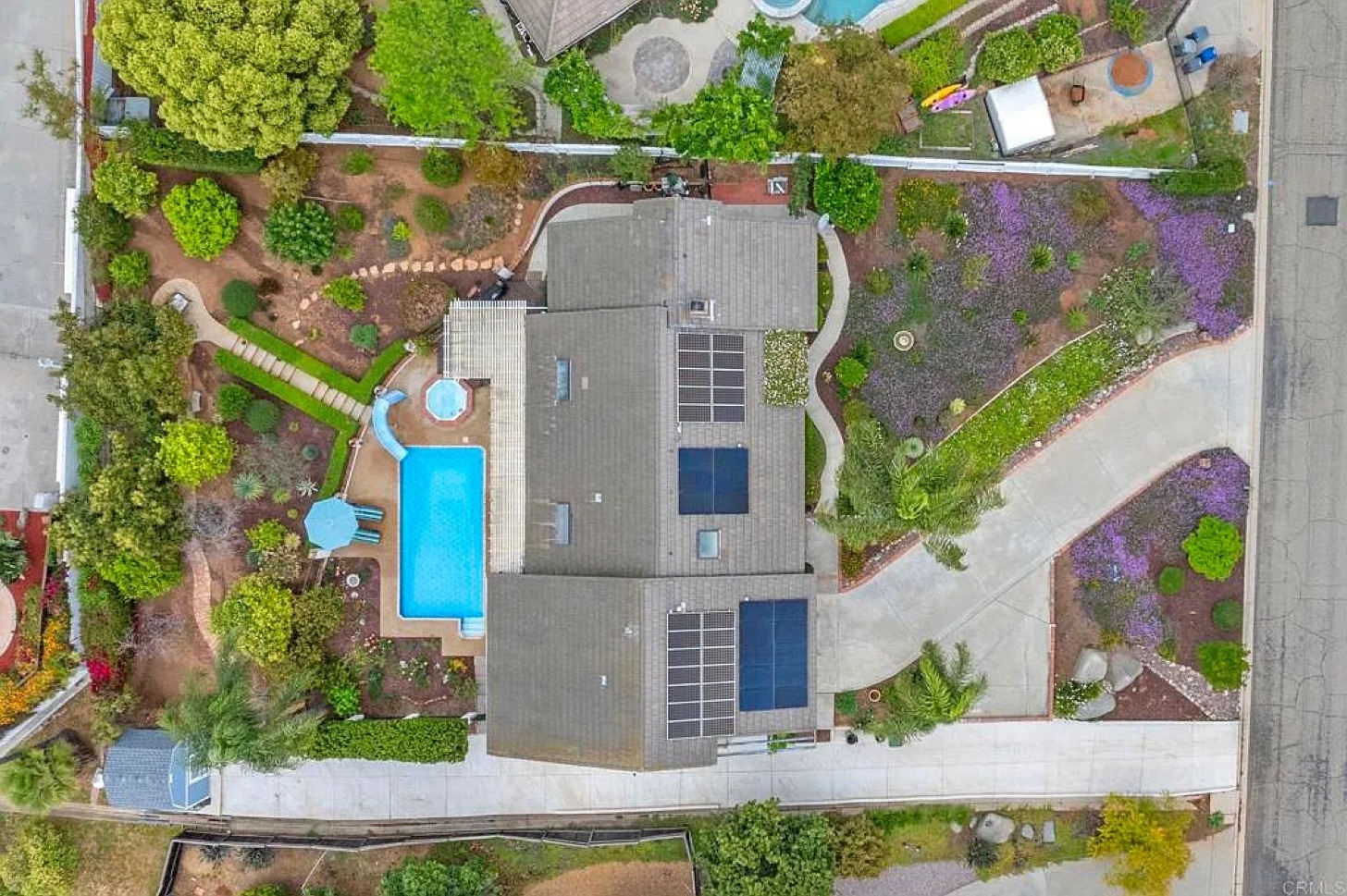 Aerial view of a managed home with a swimming pool, solar panels and landscaped grounds